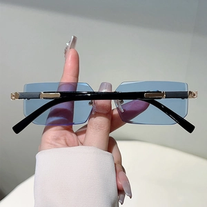 Close-up of rimless blue lens sunglasses with golden metal decorative temple details