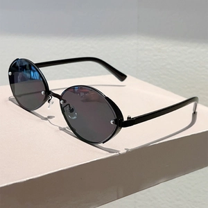 Detail view of oval sunglasses featuring silver rivets on dark black lenses with thin temples