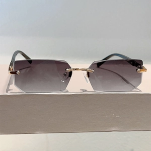 Detail of rimless rim-cut sunglasses with gradient grey lenses and golden metal temples