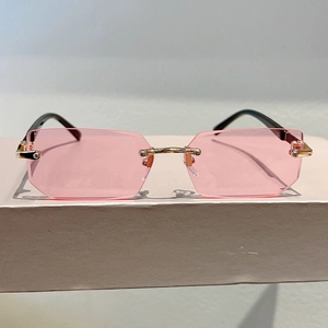 Detail of rimless pink octagonal sunglasses with gold metal bridge and black temples