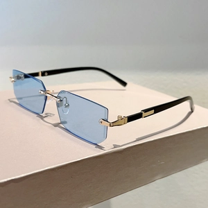 Detail of rimless rectangle sunglasses with light blue lenses and gold metal accents