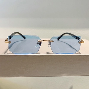 Detail of rimless rectangle sunglasses with light blue lenses and gold metal nose bridge