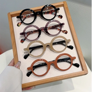 Detailed display of vintage round eyeglass frames in four assorted colors on a wooden tray