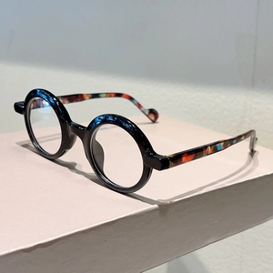 Close-up of retro round glasses with tortoiseshell temples on pink pedestal surface