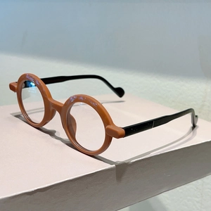 Detail view of round retro glasses with orange frames and slim black temples on a box