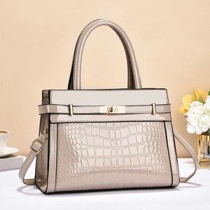 Close-up of beige patent leather tote bag with crocodile texture and gold metal buckle