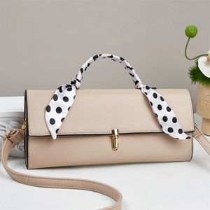 Detail of beige faux leather crossbody bag with polka dot scarf and gold twist lock