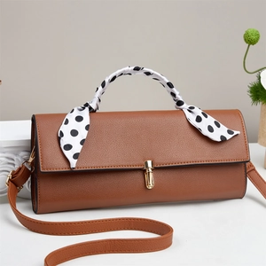 Detail of brown leather handbag with gold metal clasp and polka dot scarf handle