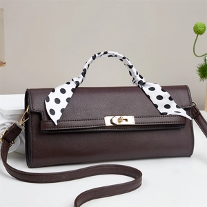 Detail of dark brown pebble leather bag with gold twist lock and polka dot scarf