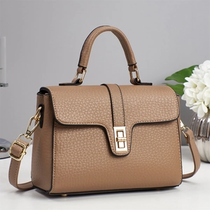 Detail view of tan crossbody bag with lychee grain texture and golden twist lock