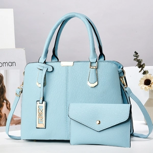 Detail einer hellblauen Handtasche aus Kieselleder mit Golddekor und kleiner Tasche