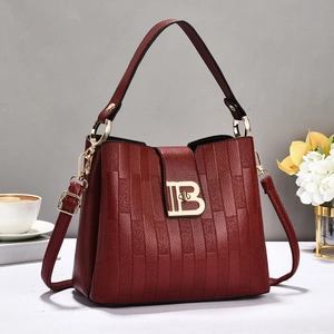 Close-up of burgundy leather handbag with vertical embossed texture and gold metal clasp