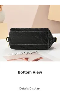 Dettaglio del fondo della borsa in pelle nera con cuciture bianche e anelli in metallo oro