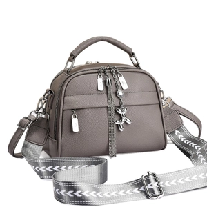 Sac à main gris en cuir grainé avec détails argentés et bandoulière tissée, vue de côté