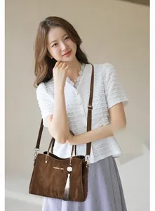 Close-up of deep brown leather handbag with gold hardware and white tassel detail