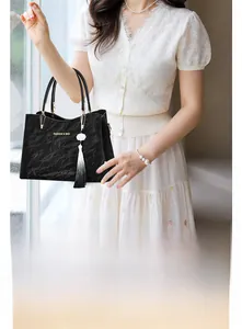 Detail of black pleated handbag with gold lettering and floral tassel pendant charm