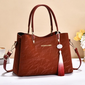 Elegant dark red textured faux leather handbag with gold lettering and floral tassel