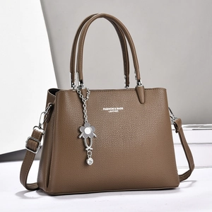 Detailed texture of dark brown pebbled leather handbag with flower charm and strap