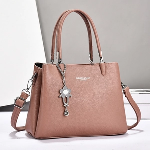 Detail of pink faux leather handbag showing lychee texture and floral metal charm