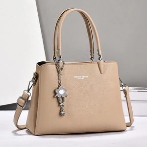 Chic beige lychee leather tote bag with top handles and floral pendant charm