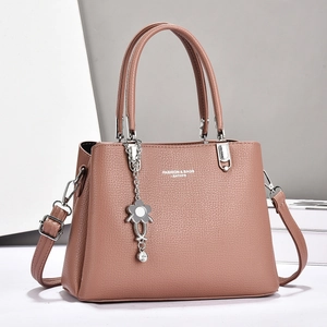 Détail du sac à main en cuir rose avec pendentif fleur et bandoulière amovible