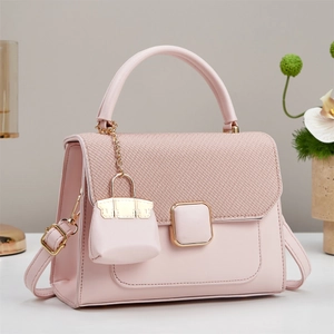 Elegant pink crossbody handbag with gold buckle and mini charm in a refined setting