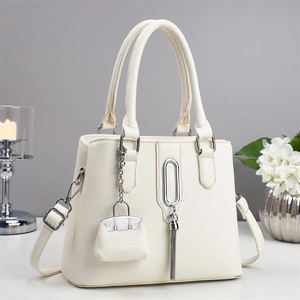 Elegante cremeweiße Lederhandtasche mit silbernen Beschlägen und modischem Quasten-Akzent
