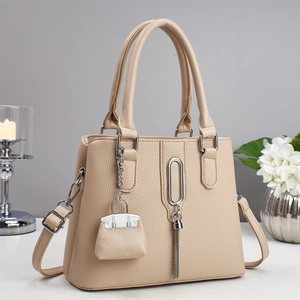 Detailansicht der beigen Kieselmaserung und Metallquaste an dieser Damenhandtasche