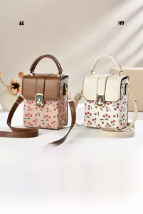Detail of square crossbody bags with cherry prints, metal clasp and adjustable strap