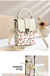 Detailed close-up of cherry print crossbody bucket bag with metallic twist lock hardware
