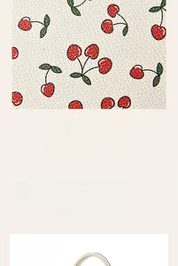 Macro shot of white pebble grain leather with vibrant cherry and green leaf print detail