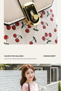 Detail of cherry print on cream leather crossbody bag with golden metal twist lock