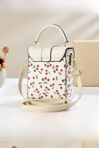 Detail view of the side and back of the cream cherry print bucket bag with gold hardware