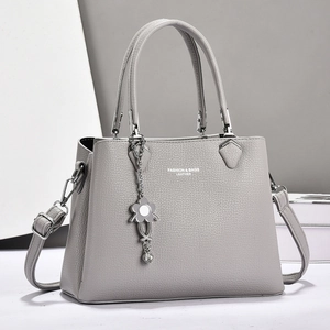 Light gray pebbled leather handbag with silver hardware and floral charm pendant