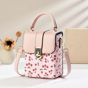 Pink mini square bag with cherry print and golden hardware on a minimalist background