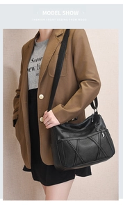 Sac bandoulière en cuir souple avec plusieurs zips porté par un mannequin