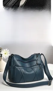 Gros plan d'un sac à main bleu paon en cuir grainé avec plusieurs poches zippées