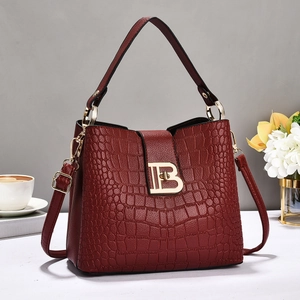 Detail of burgundy crocodile pattern handbag with gold B letter metal buckle closure