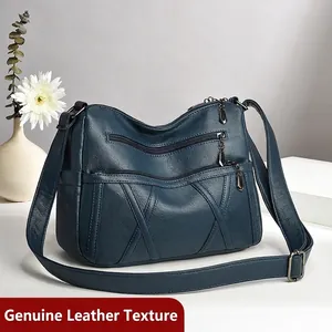 Sac bandoulière en cuir bleu foncé avec poches zippées et texture grainée