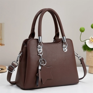 Brown lychee leather tote bag with silver hardware and star pendant on a gray background