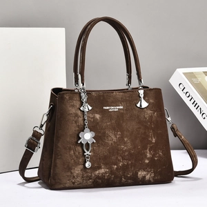 Brown vintage textured leather tote bag with top handles and floral charm accessory