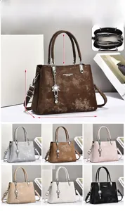 Detailed close-up of textured leather handbag with metallic floral pendant and internal zipper