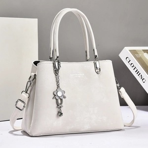Elegant white matte leather tote bag with silver flower charm and adjustable shoulder strap