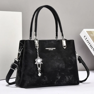 Close-up of black leather tote with silver buckle and flower pendant detail