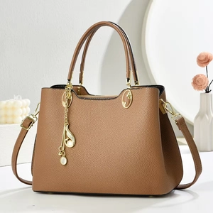 Detail of brown litchi pattern leather handbag with gold hardware and tassel ornament