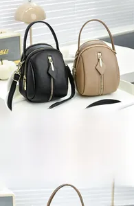 Close-up of litchi grain texture and dual zipper detail on black and khaki mini tote bags