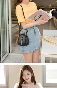 Detail of black lychee leather crossbody bag with gold zippers and multi-compartment design