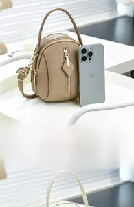 Detailed comparison of brown leather mini crossbody bag with phone for size reference