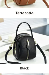 Detail of leather crossbody mini bags in tan and black with gold zipper compartments