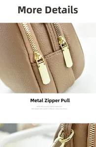 Detail of premium golden hardware zippers and lychee grain leather on a brown crossbody bag